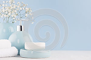 Light pastel blue acessories for bath and skin and body care product - soap, soap dispenser, towel on white wood table.