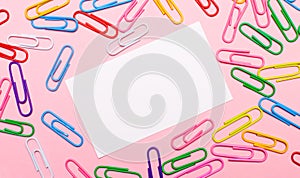 On a light pink background, colorful bright paper clips and a white blank card with a place to insert text in the center. Template