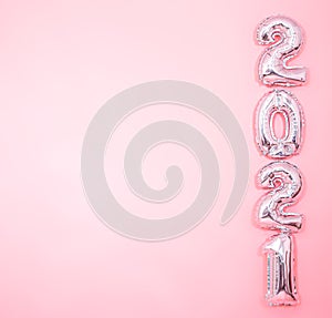 Light pink background with silver balloons in the form of numbers 2021 photo