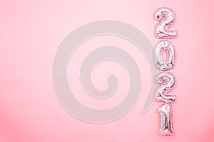 Light pink background with silver balloons in the form of numbers 2021 photo