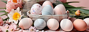 Light pink and blue colored eggs and spring flowers on pink background, beautiful Easter banner in delicate colors