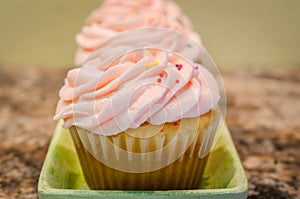 Light pink butter cream frosting on cherry chip cupcakes