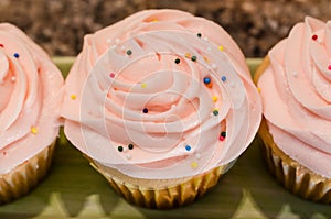 Light pink butter cream frosting on cherry chip cupcakes