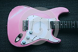 Light pink electric guitar in a purple texture background