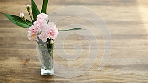 Light pink flowers in vase on wood background