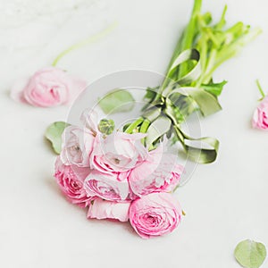 Light pink spring ranunkulus flowers bouquet on white marble background