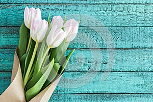 Light pink tulips bouquet on turquoise wooden tabletop with copy space