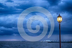 Light Post at nigth near sea with stom background photo