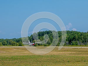 Light private plane is landing on a small airfield on a sunny summer day