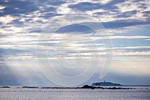 Light ray over the sea with the view of torii gate and light house in the distance