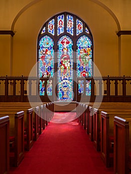 Light rays from stained glass window light up church aisle