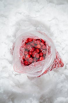 Light red cherries frozen in a plastic bag on a grinded ice. top view.