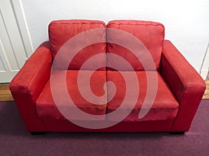 Light red leather sofa in front of white wall in the corridor.