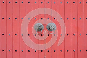 A light red rose maroon painted oriental gate with studs and lion beasts knockers