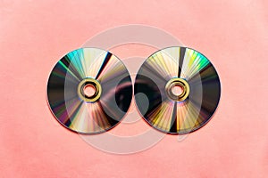 Light reflected compact discs on pink paper background