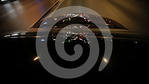 Light reflections on car glass and car hood at night. Night driving