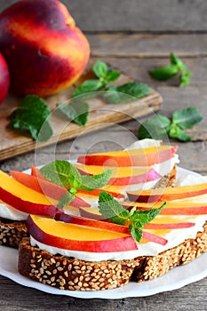 Light sandwiches with cream cheese, nectarines and mint on a serving plate and on a vintage wooden table. Healthy sandwich recipe