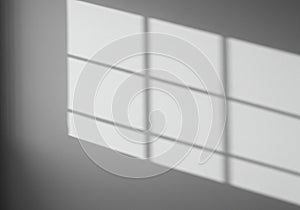 Light and shadow create a grid pattern on a smooth, pale gray wall. The shadow