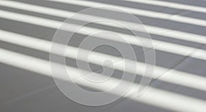 Light and shadow pattern created by window blinds on a flat, white surface. The light