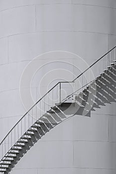 Light and shadow on spiral staircases surface of oil storage fuel tanks in black and white style