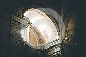 The light is shining through an window in an historic catholic church