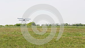 Light single-engine aircraft lands on the field airfield. The aircraft sits on the green grass