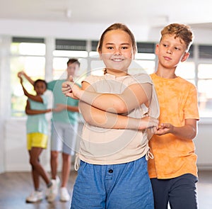 Light-skinned boy and girl dance in pairs and rehearse dance before performing on main floor.