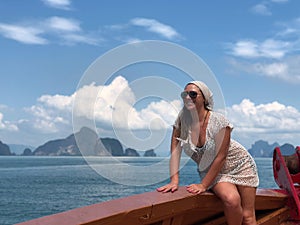 Light-skinned girl in beach clothes on Board the ship on a hot summer day against the sea of Islands of Thailand Phu