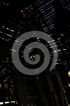 Light and sky shown through the ceiling of a collapsing wooden farm building