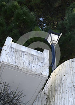 A light stone balcony and a lantern against a background of dense dark pine