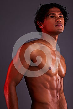 Light, strong and man chest in a studio with art lighting and thinking with muscles and fitness. Focus, isolated and