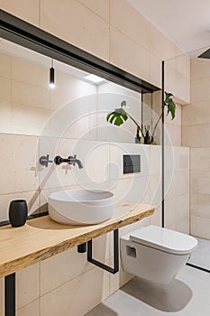 Light style bathroom with a toilet bowl, big mirrors and a sink and a glass shower cabin. The concept of a stylish but