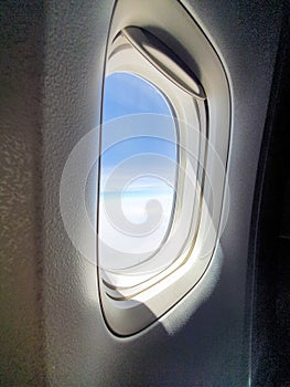 light, sunbeam through aircraft window, airplane window view on blue sky, aviation, travel, tourism