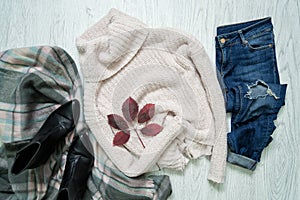 Light sweater, scarf, jeans and autumn leaf. Fashionable concept