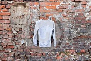 Light sweater sweater hangs on a hanger on a brick wall on the street, women`s clothing