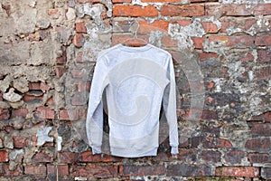 Light sweater sweater hangs on a hanger on a brick wall on the street, women`s clothing