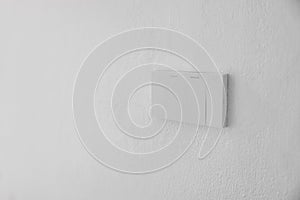 Light switch, Close-up White plastic mechanical switch mounted on a white wall