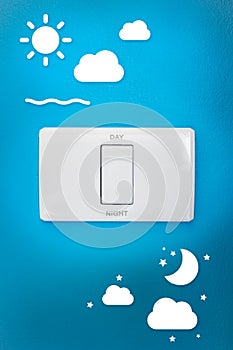 Light switch, day, night on a blue wall.