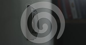 Light switch on a white wall, blurred books in the background.