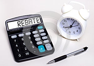 On the light table there is a black calculator with the text REBATE on the scoreboard, a pen and a white alarm clock. Business