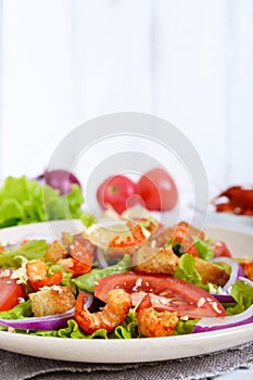 Light tasty salad with meat of a cancer, shrimps, lettuce, garlic croutons, tomatoes, red onion