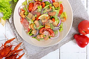 Light tasty salad with meat of a cancer, shrimps, lettuce, garlic croutons, tomatoes, red onions