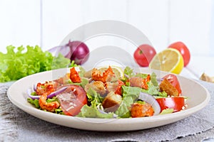 Light tasty salad with meat of a cancer, shrimps, lettuce, garlic croutons, tomatoes, red onions