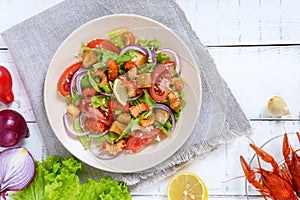 Light tasty salad with meat of a cancer, shrimps, lettuce, garlic croutons, tomatoes, red onions on a white background.