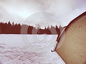 Light tent set on snow in winter forest in mountains