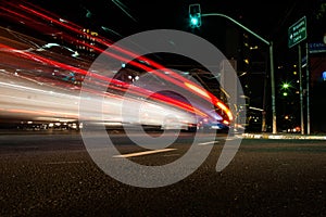 Light trails of vehicle in a street with green traffic light.