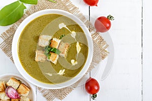 Light vegan spinach cream soup with crispy croutons in a bowl on a white background