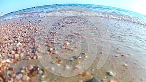 Light waves surf surf on the sandy shore on a clear sunny day, the Red Sea, a view from below from the shore, super wide