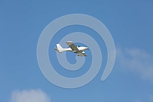 A light white plane flies across the blue sk