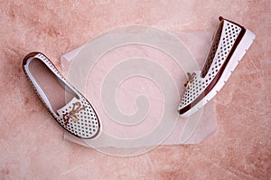 Light women`s shoes with a bow and perforation on a brown background